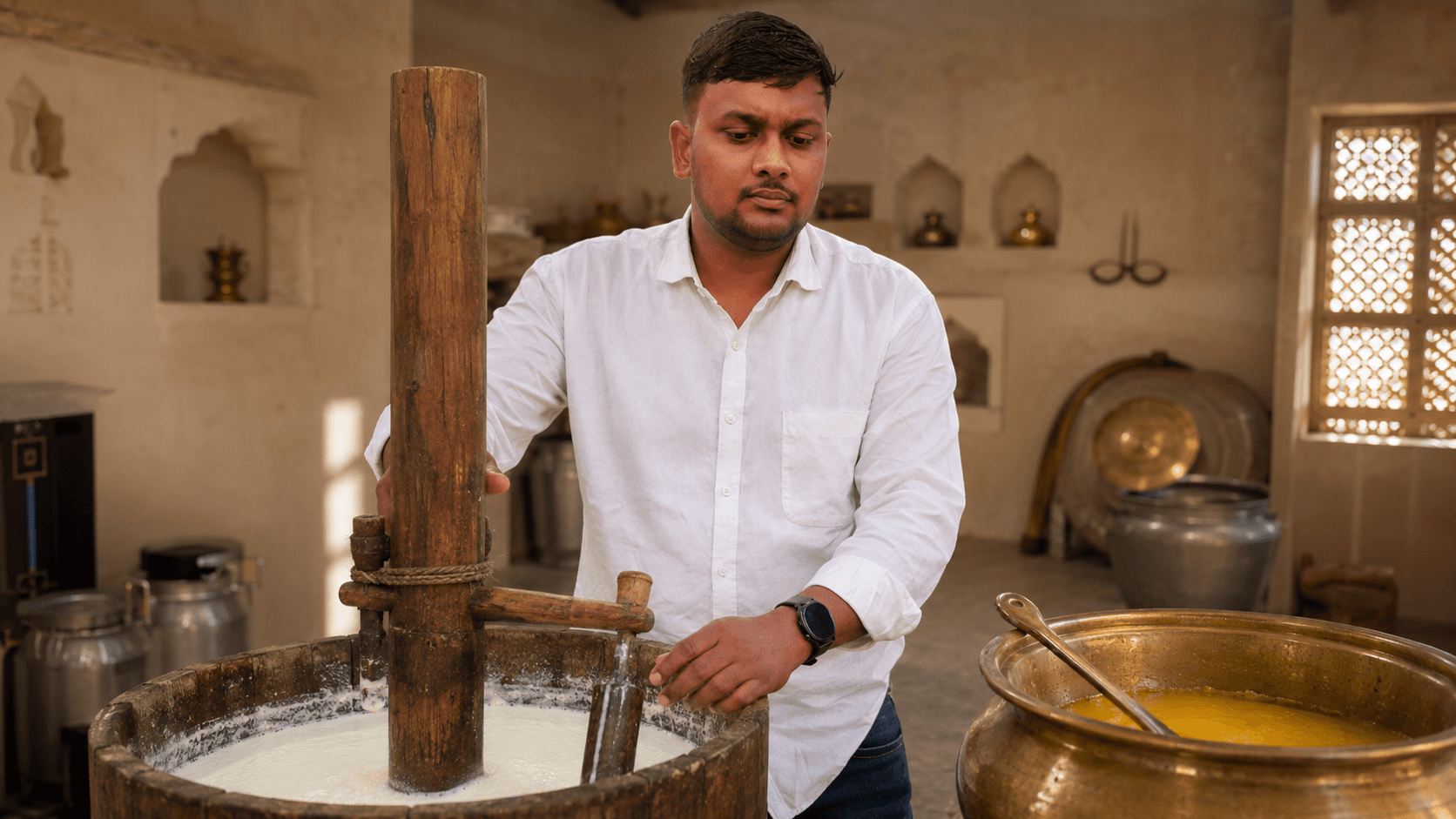 Organic Jaipur founder hand-churning curd with a traditional wooden bilona